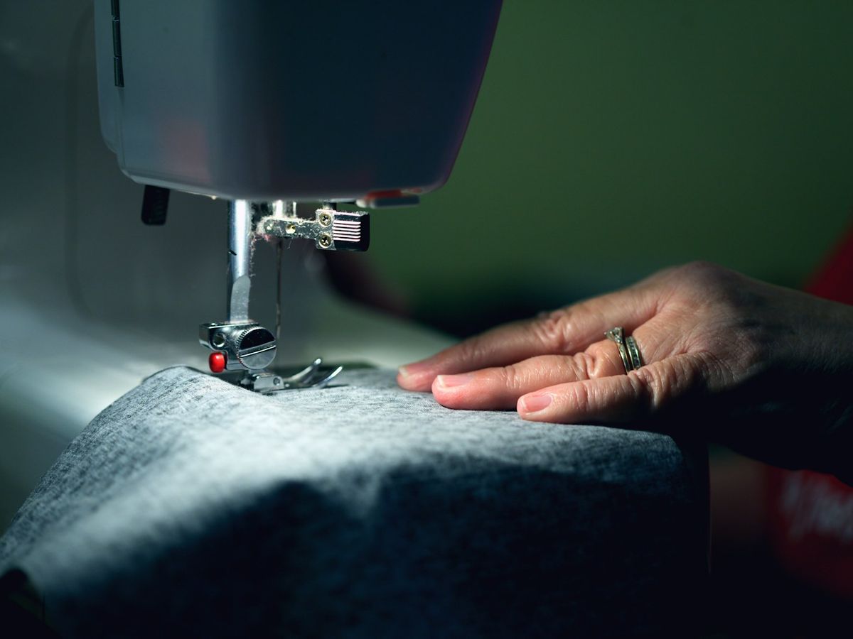 Manos cosiendo una prenda a máquina en un taller de arreglos de ropa